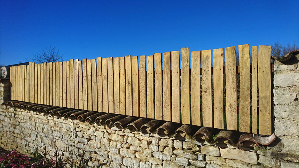 Barrière en volige de bois fixée sur un muret en pierres sèches